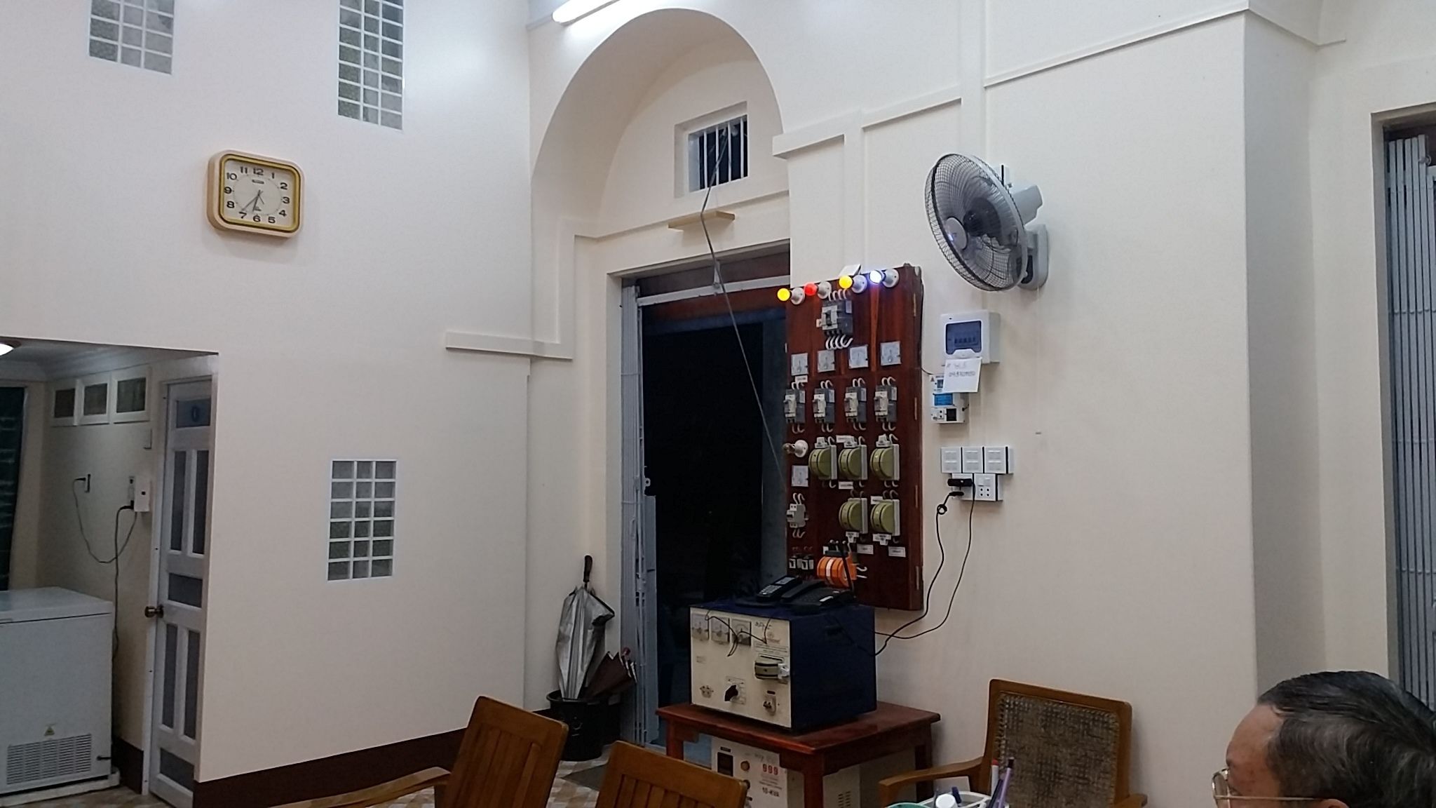 Ein Zimmer mit einer Uhr, einem Ventilator und einer Bedienfeld an der Wand.
