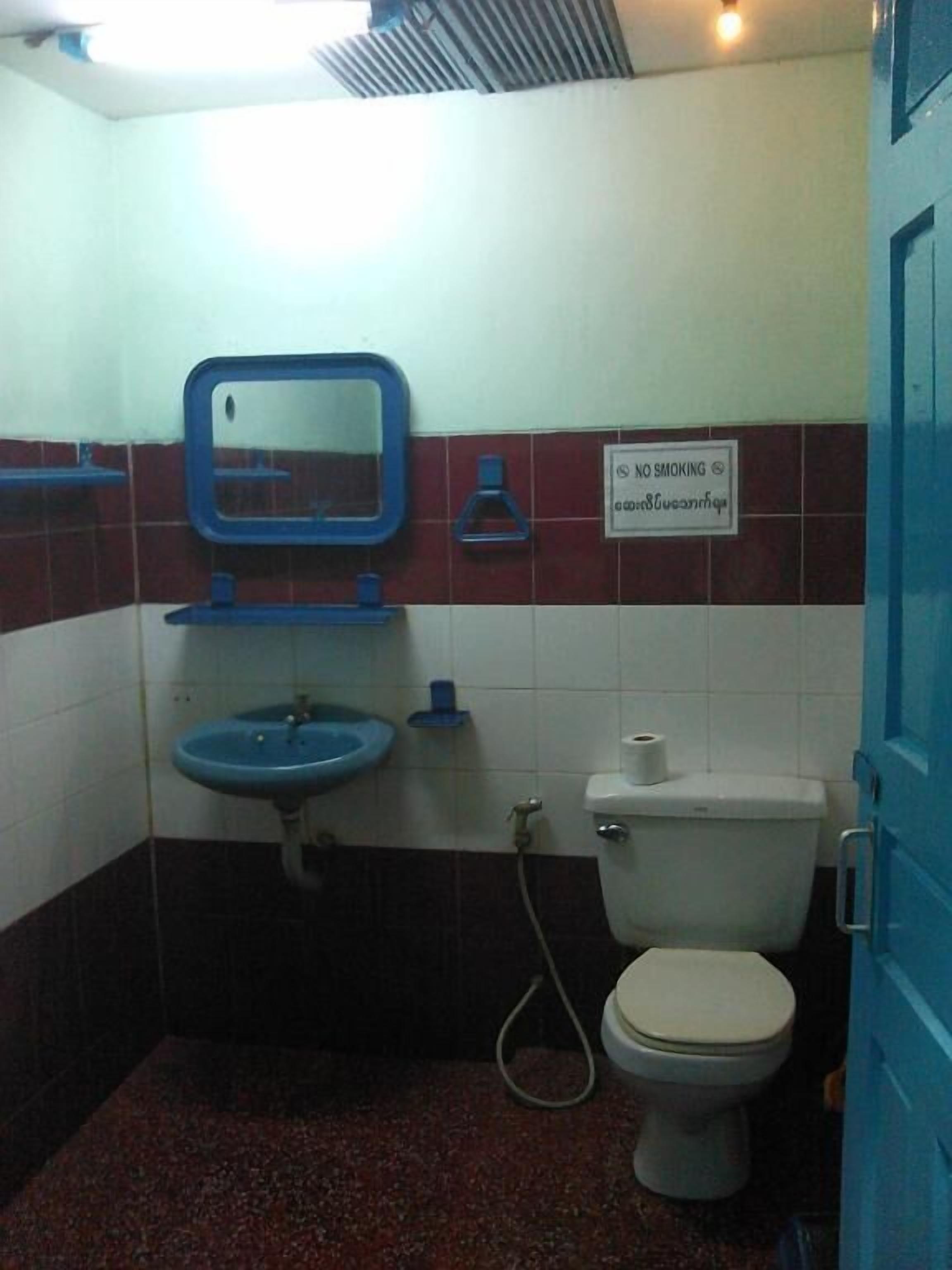 Ein kleines Badezimmer mit blauem Waschbecken, Toilette und Spiegel.