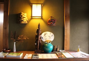 A wooden table with a vase, a decorative mask, and a window with light.
