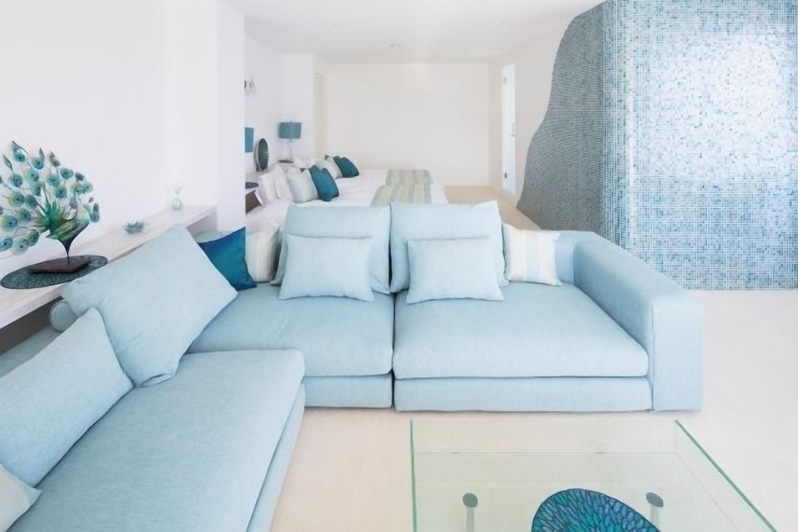 A modern living room with a light blue sofa, a glass coffee table, and a decorative peacock sculpture.