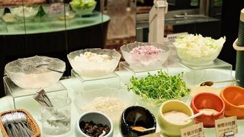 Buffet variat amb diferents plats i condiments, incloent un bol de pollastre desfiladí, un bol de col desfilada i un bol de brots.