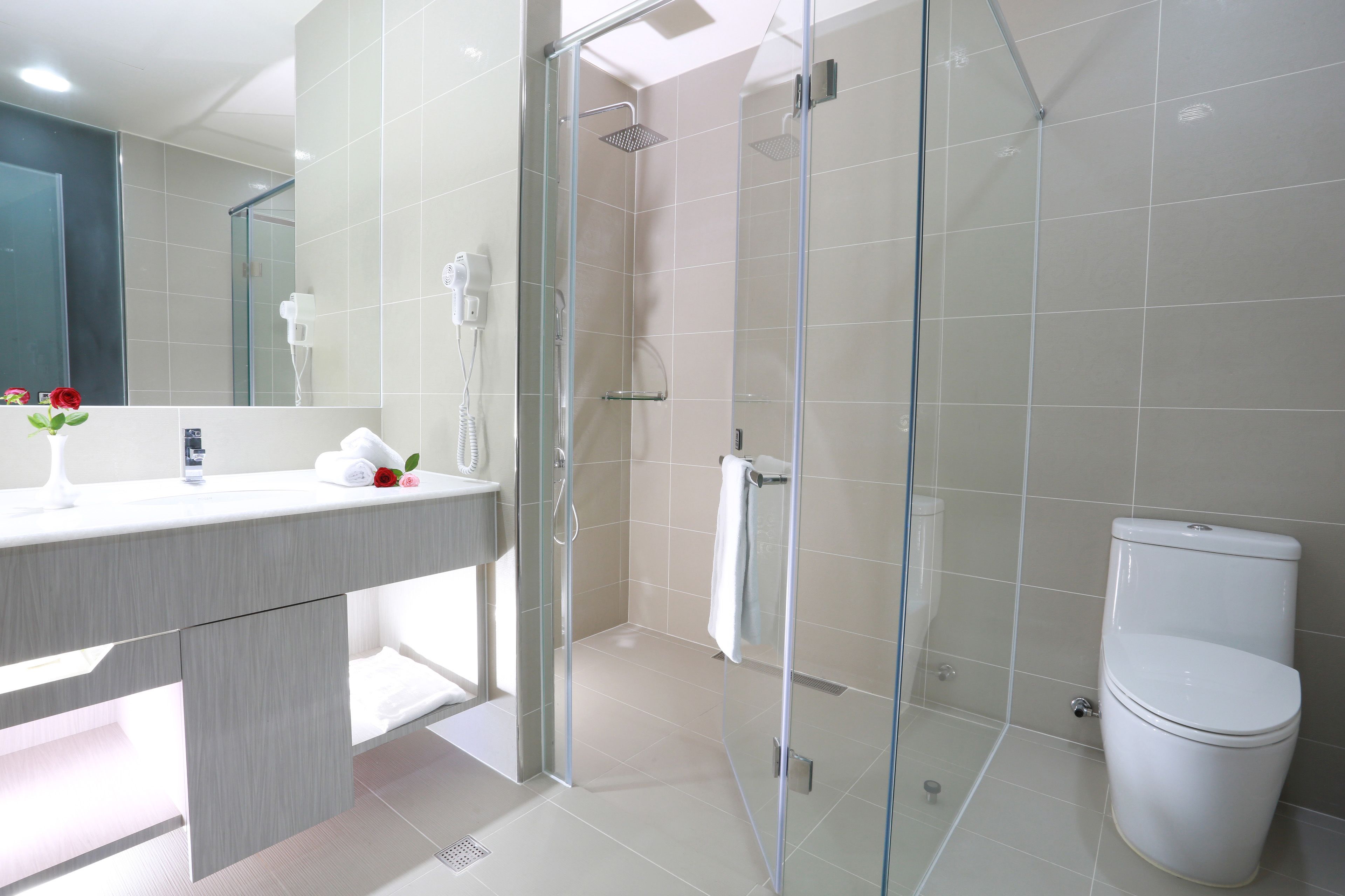 Un baño moderno con ducha de vidrio, inodoro blanco y tocador con espejo.