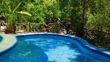 Una piscina al aire libre, sombrillas, tumbonas