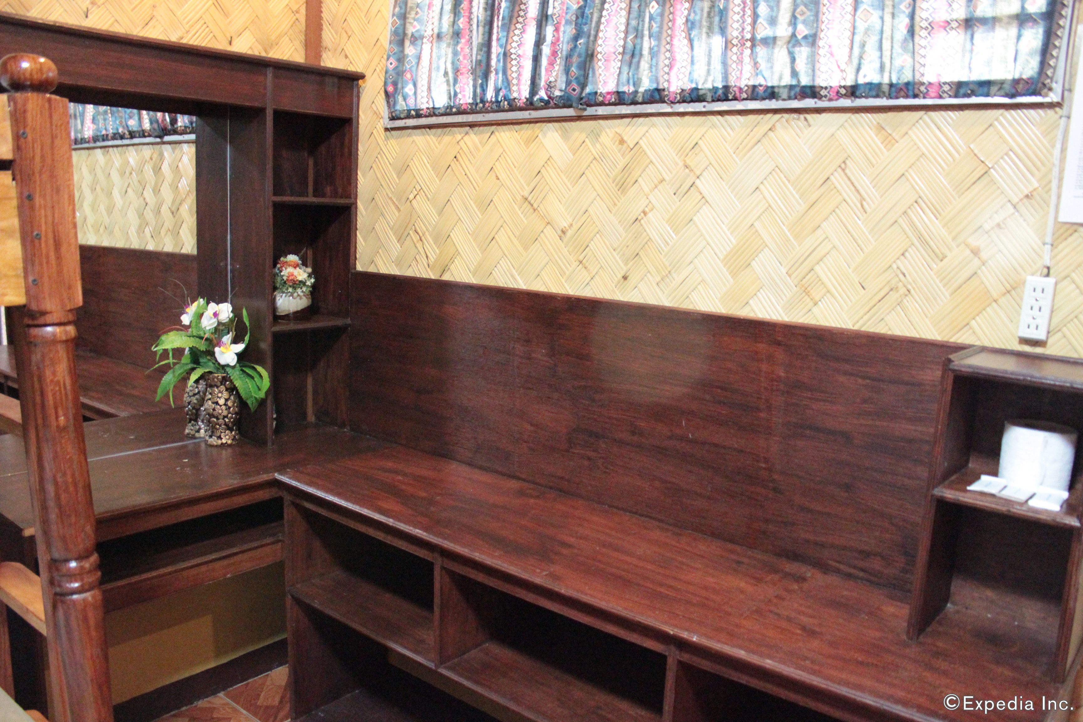 A wooden bench with a woven wall behind it.