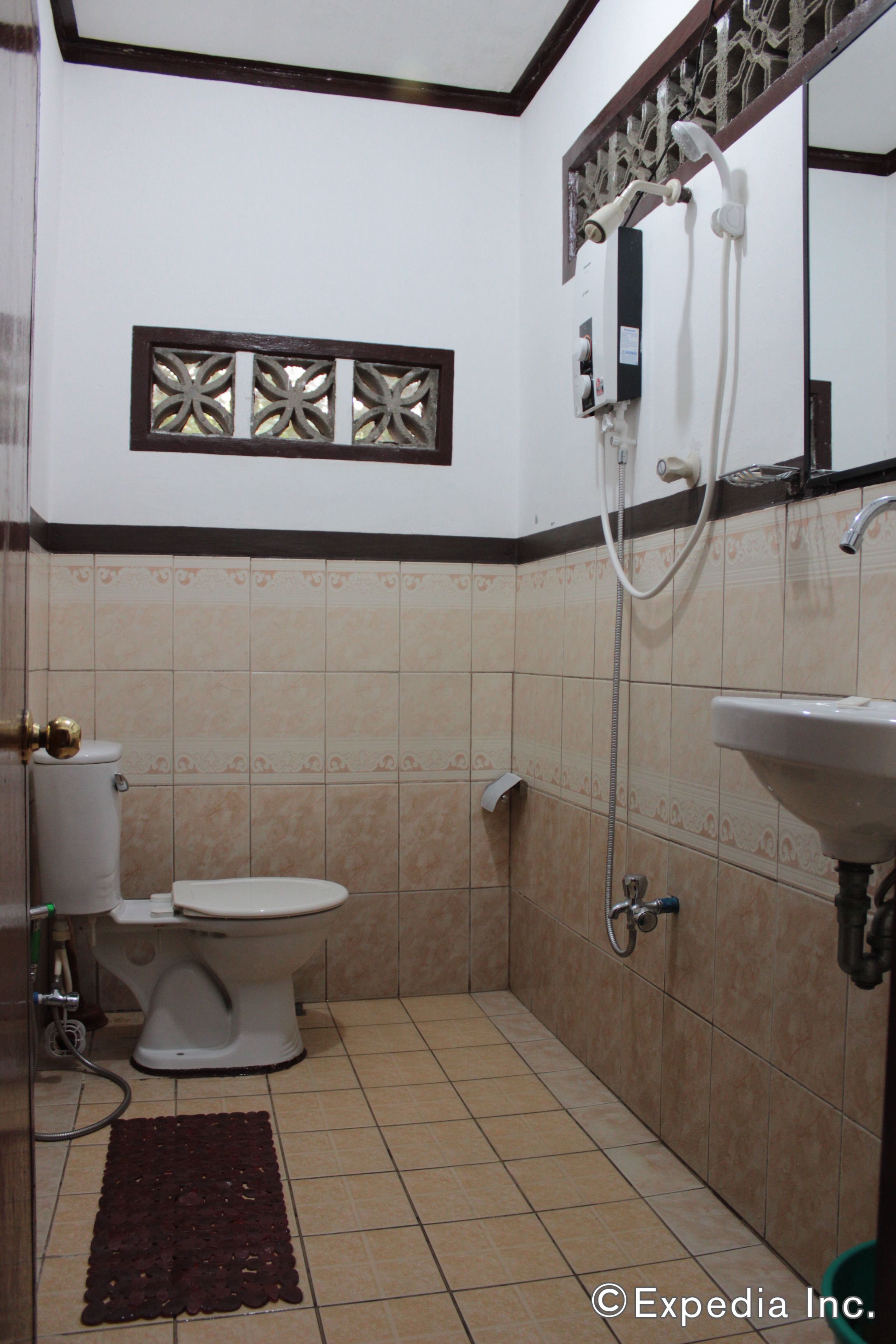 A bathroom with a toilet, shower, and sink.
