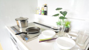 A kitchen with a stove, pots, bowls, chopsticks, and a potted plant. - Shukusai Art stay in Tofukuji (Kyoto)