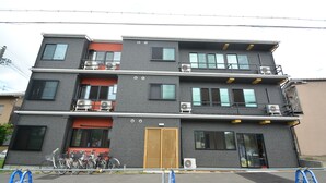 A multi-story building with balconies, air conditioning units, and a wooden door. - Shukusai Art stay in Tofukuji (Kyoto)
