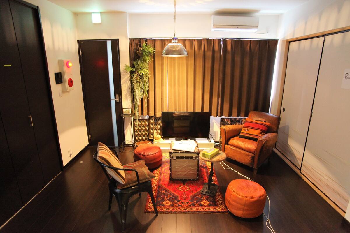 A modern living room with a sofa, ottoman, and a television.