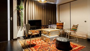 A modern living room with a flat-screen TV, a sofa, a coffee table, and a patterned rug. - Shukusai Art stay in Tofukuji (Kyoto)