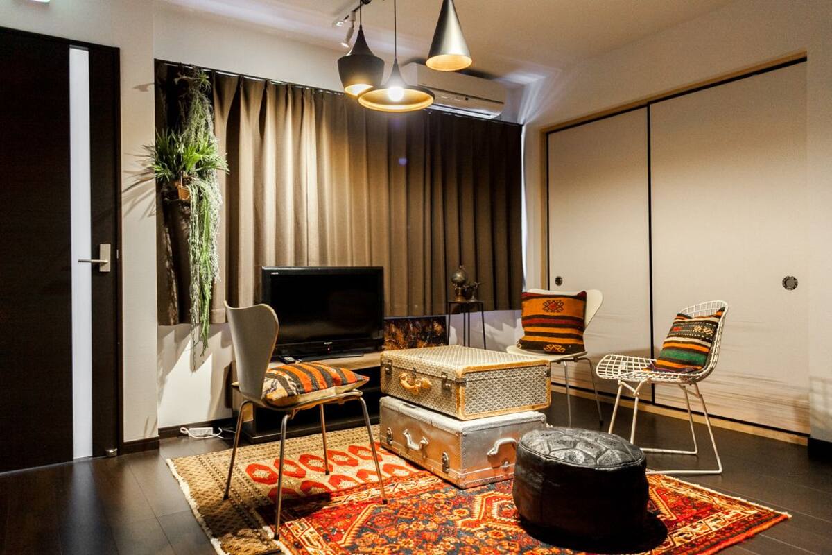 A modern living room with a flat-screen TV, a sofa, a coffee table, and a patterned rug.