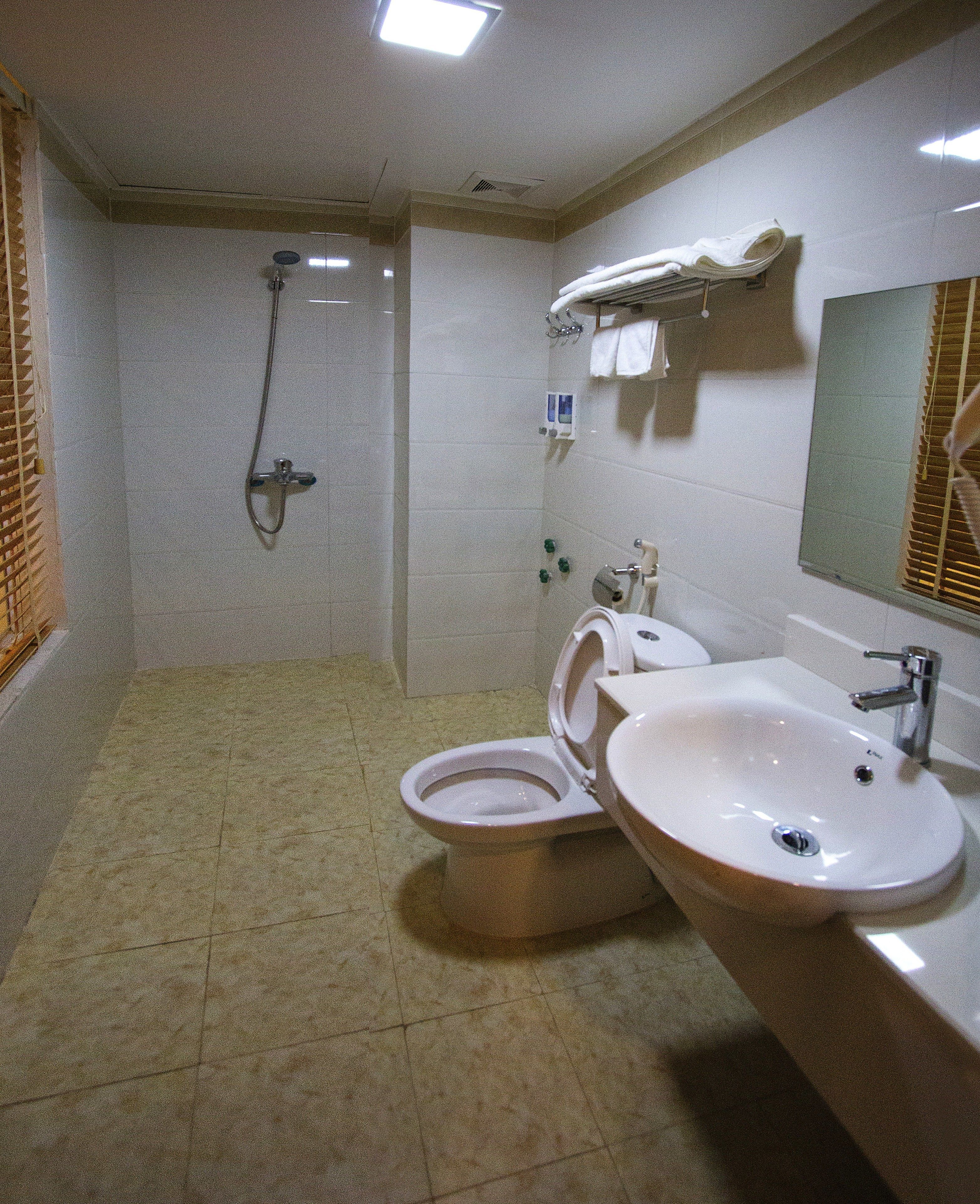 A bathroom with a shower, toilet, and two sinks.