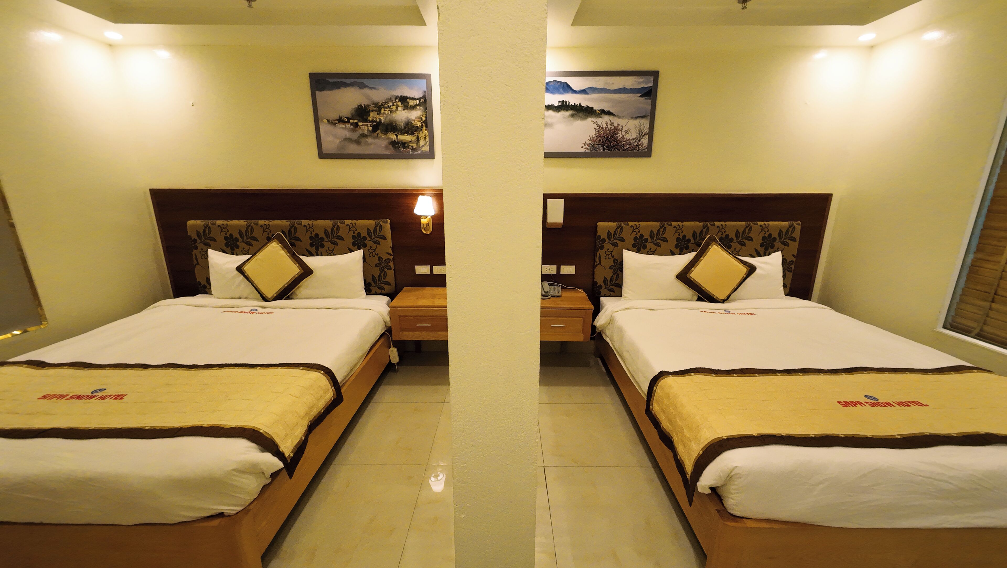Habitación de hotel con espejo, dos camas, cabeceros, mesitas de noche y lámparas.