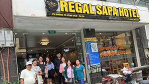 Un grupo de personas frente a un hotel con un cartel que dice 'Regal Sapa Hotel' y un número de teléfono.