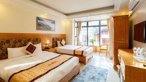 Habitación de hotel con dos camas, un escritorio, una silla y un televisor.