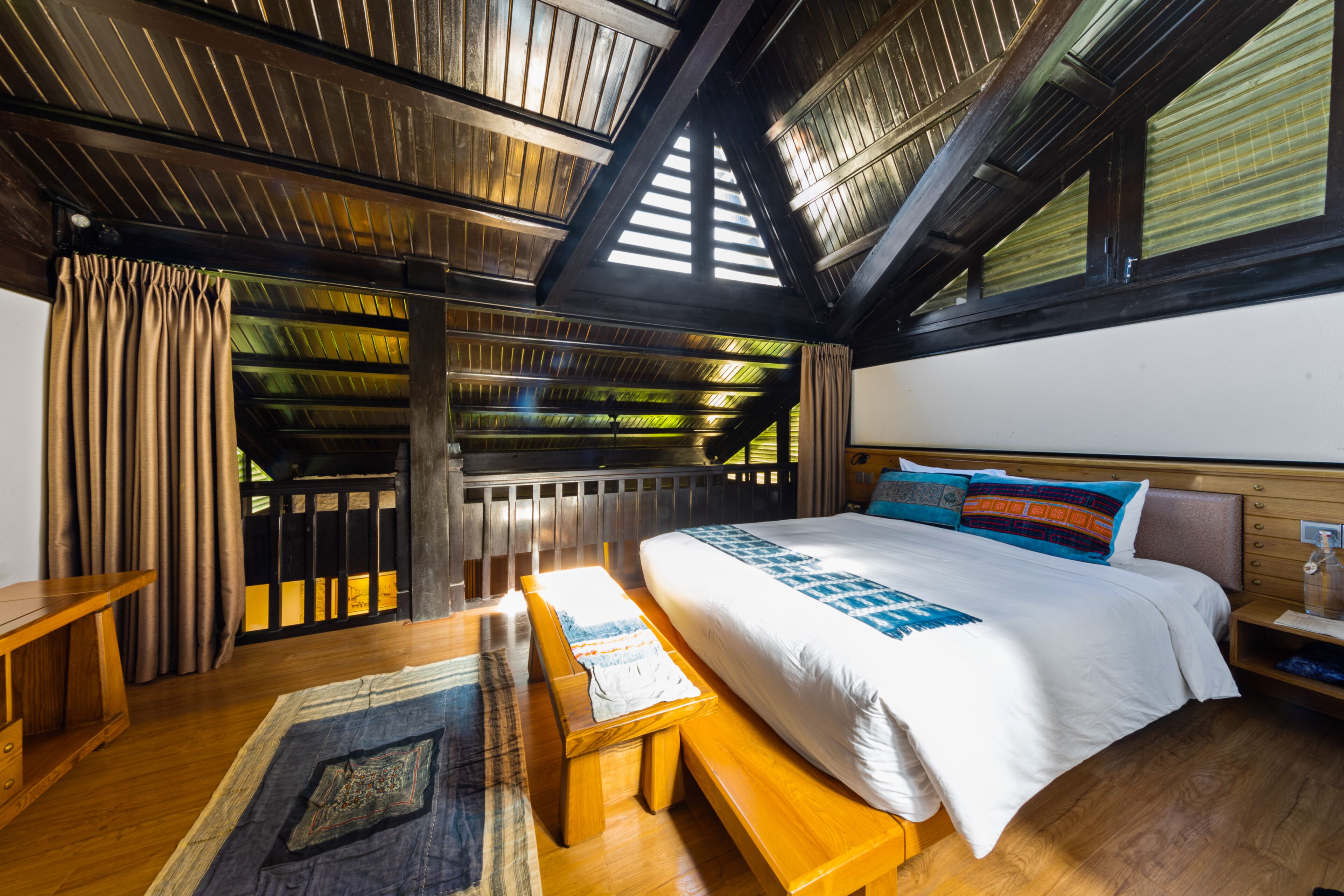 Une chambre avec un grand lit, des meubles en bois et un plafond en pente doté de fenêtres de toit.