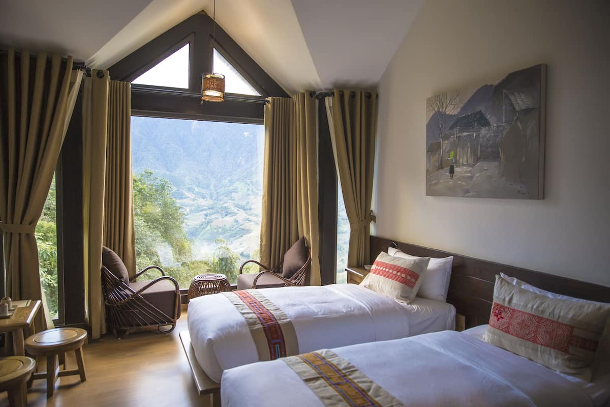 Une chambre d’hôtel avec deux lits, un coin repas et une vue sur les montagnes.