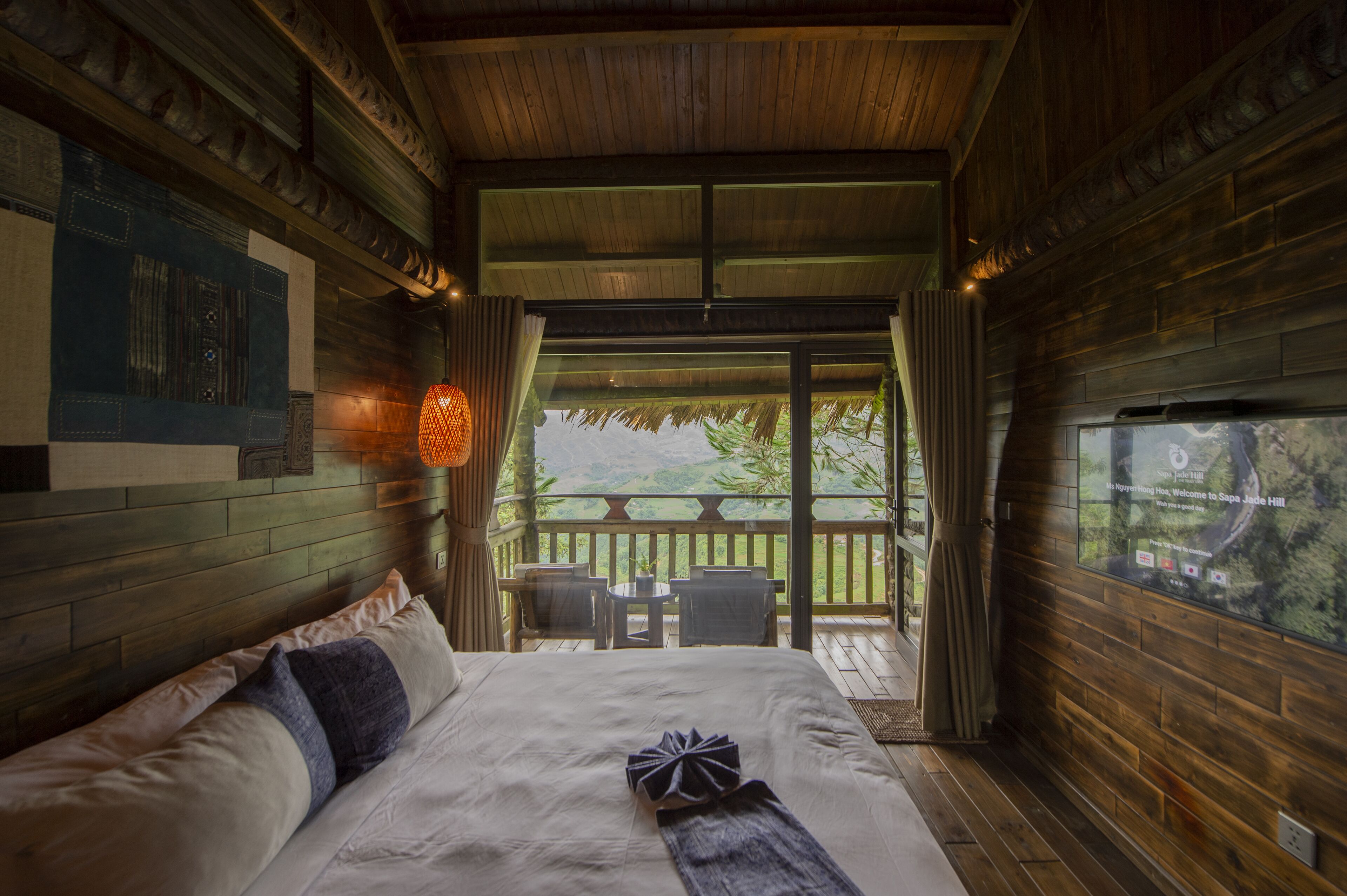 Ein Schlafzimmer mit einem großen Bett, Holzwänden, einem Balkon mit Blick und einem kleinen Tisch mit Stühlen.