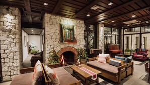 A cozy living room with a stone fireplace, wooden furniture, and a large painting on the wall. - Sapa Jade Hill Resort & Spa (Sa Pa)