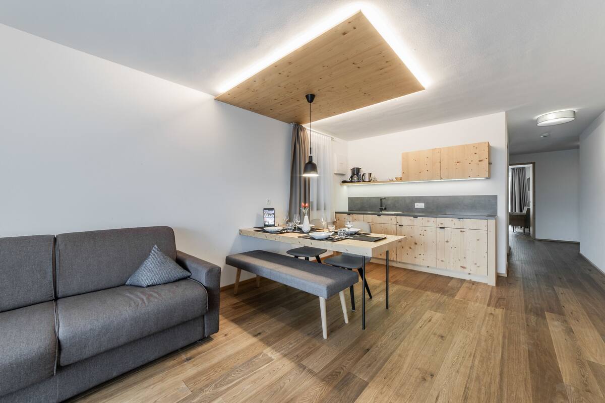 A modern kitchen with wooden cabinets, a dining table, and a bench.