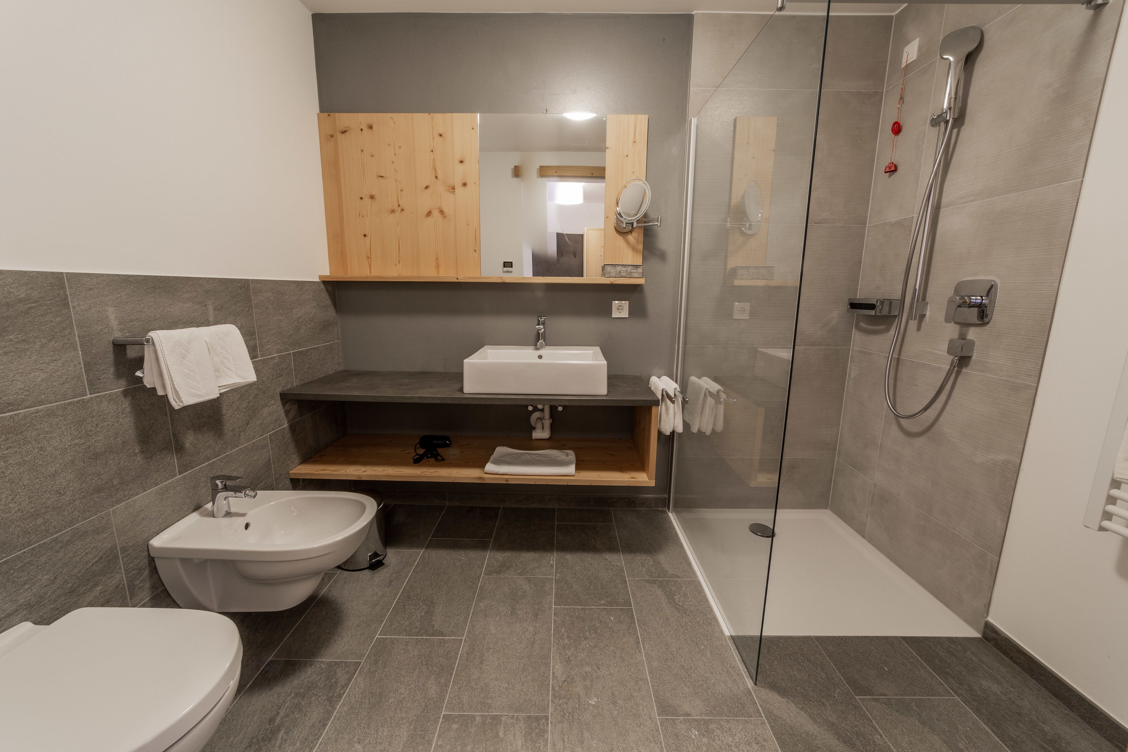 A modern bathroom with a bidet, sink, and glass-enclosed shower.