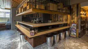 Une cuisine moderne avec un comptoir en bois, des tabourets en acier inoxydable et un luminaire suspendu.