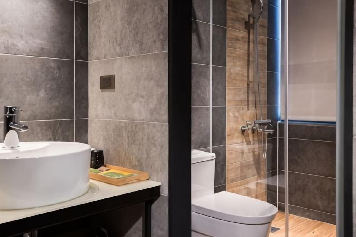 Een moderne badkamer met een wit wastafelmeubel, toilet en een douchecabine met glazen wanden.