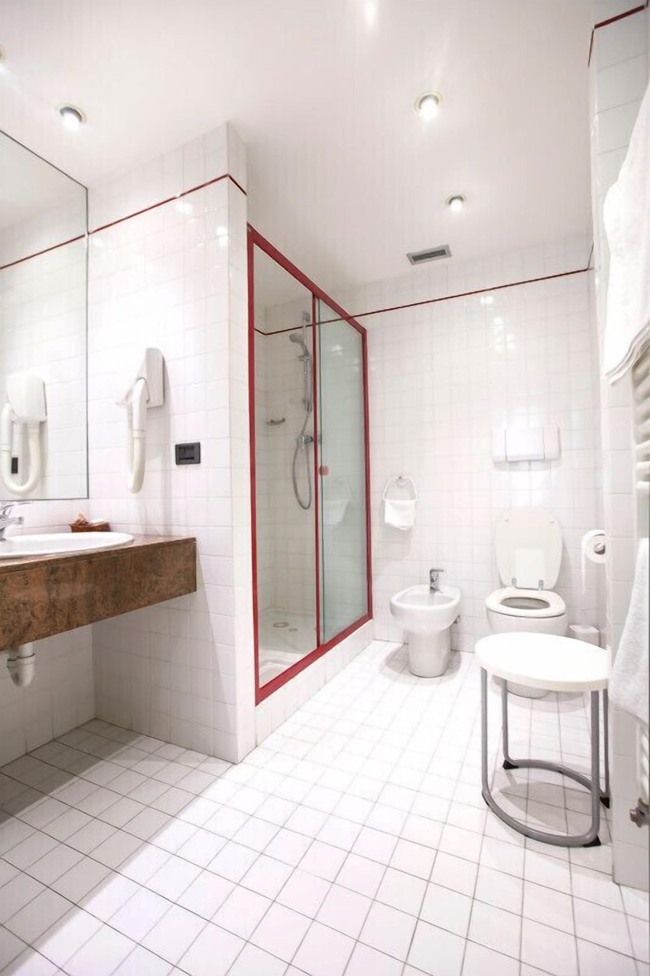 Ein modernes Badezimmer mit einer gläsernen Duschkabine, einem Waschtisch mit Marmorplatte und einer separaten Toilette.