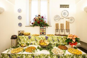 A buffet table with various food items and a floral centerpiece. - Locanda La Posta (Cavour)