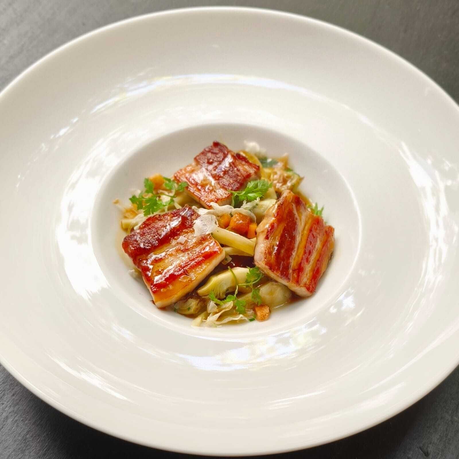 Une assiette blanche contenant un plat composé de morceaux de viande et de légumes.