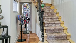 A staircase with a unique design, leading to a room with a wooden floor and a display of magazines. - Hôtel Restaurant Claude Darroze (Langon)