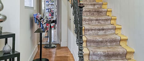 A staircase with a unique design, leading to a room with a wooden floor and a display of magazines.