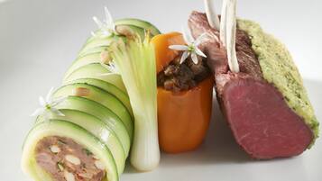 A plate with sliced vegetables, meat, and a green puree.
