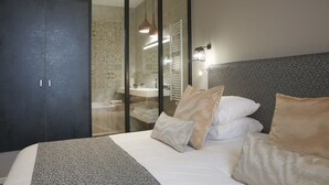 A modern bedroom with a large bed, a wardrobe, and a bathroom visible through a glass partition. - Hôtel Restaurant Claude Darroze (Langon)