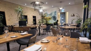 A restaurant with wooden tables, chairs, and hanging pendant lights. - Hôtel Restaurant Claude Darroze (Langon)