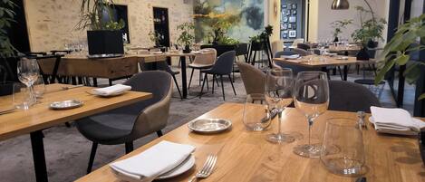 A restaurant with wooden tables, chairs, and hanging pendant lights.