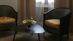 A room with two armchairs, a small table with a vase, and a floor lamp. - Hôtel Restaurant Claude Darroze (Langon)