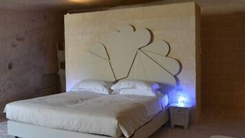 A bedroom with a bed, a nightstand, and a bathtub.