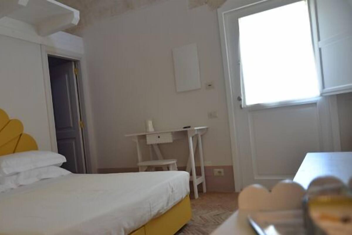A bedroom with a bed, a desk, and a window.