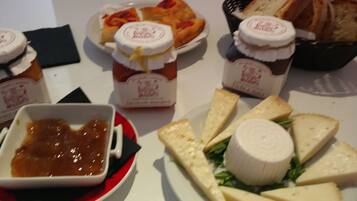 Una mesa con diferentes alimentos, incluyendo queso, pan y un recipiente pequeño con salsa.