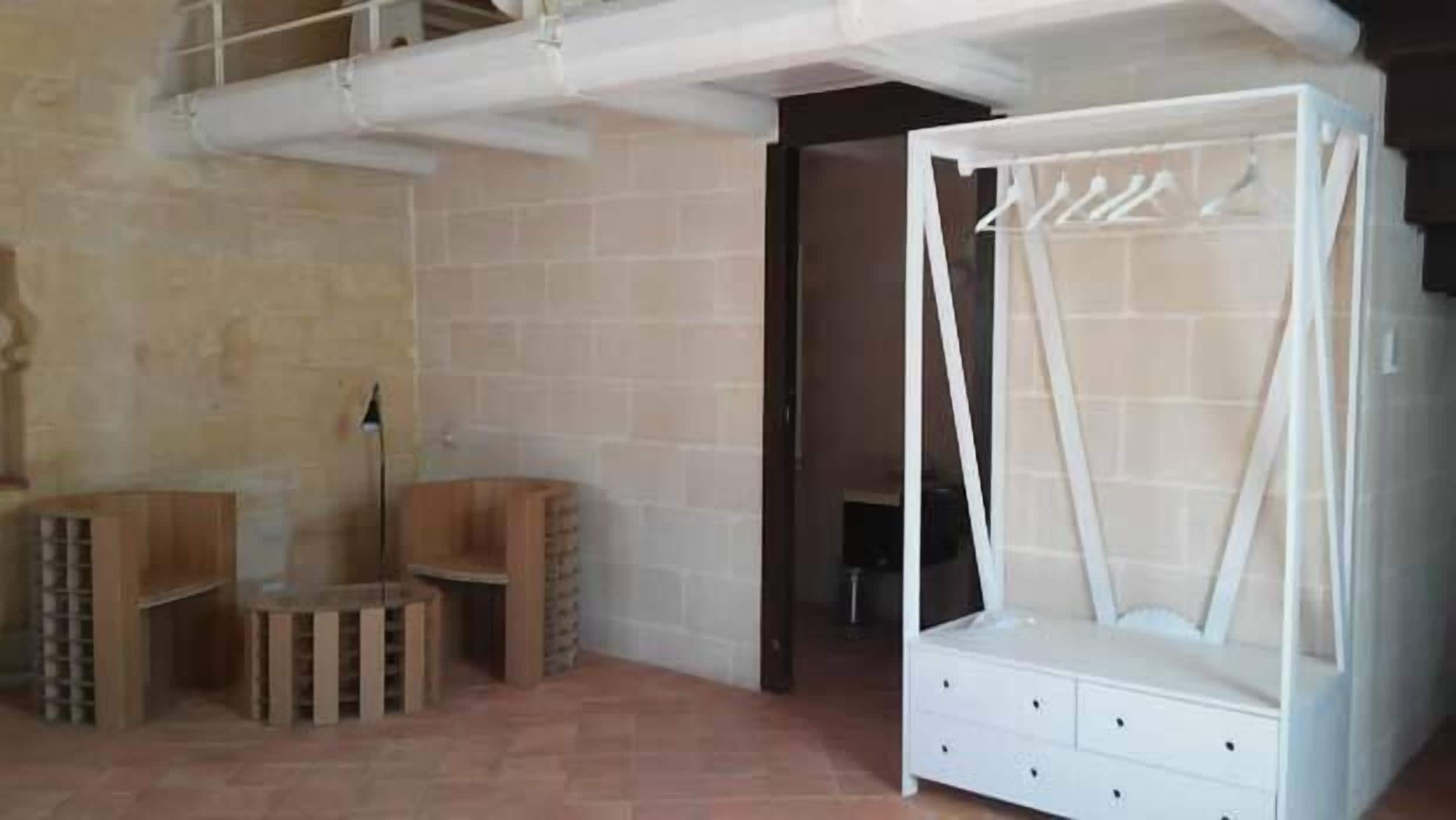 Una habitación con una cama con dosel blanco, un banco de madera y piso de baldosas.