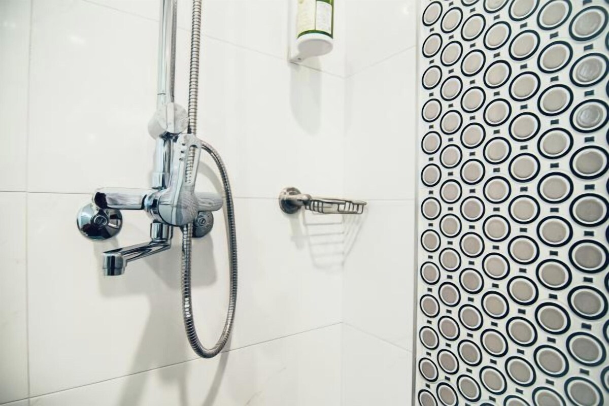 A bathroom with a shower, a towel rack, and a soap dispenser.