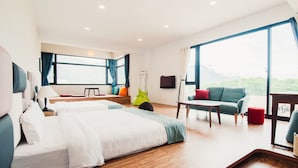A modern hotel room with two beds, a sofa, a dining table, and large windows offering a view of greenery. - Zai Yan-Yan B&B (Ji'an)