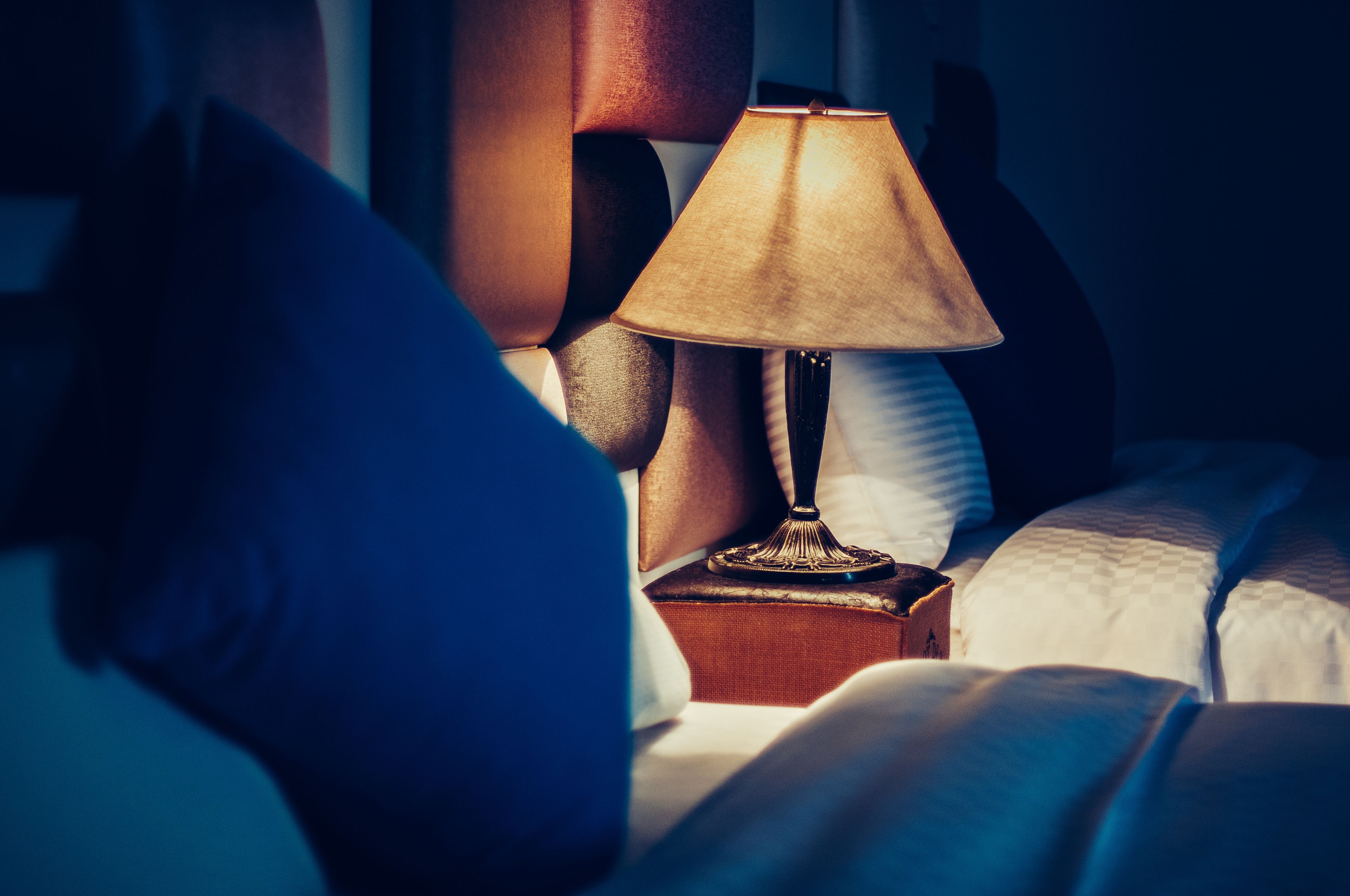 Ein Bett mit Lampe auf einem Nachttisch, Kissen und einem Buch.
