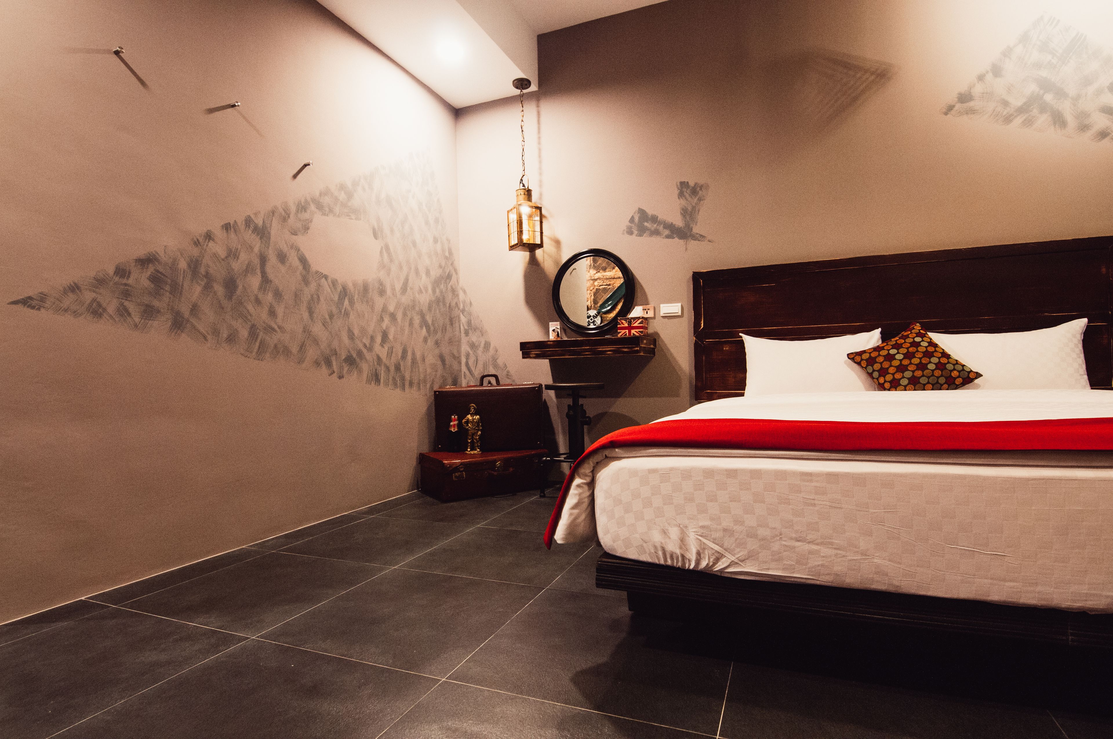 A hotel room with a bed, a nightstand, a lamp, and a suitcase.