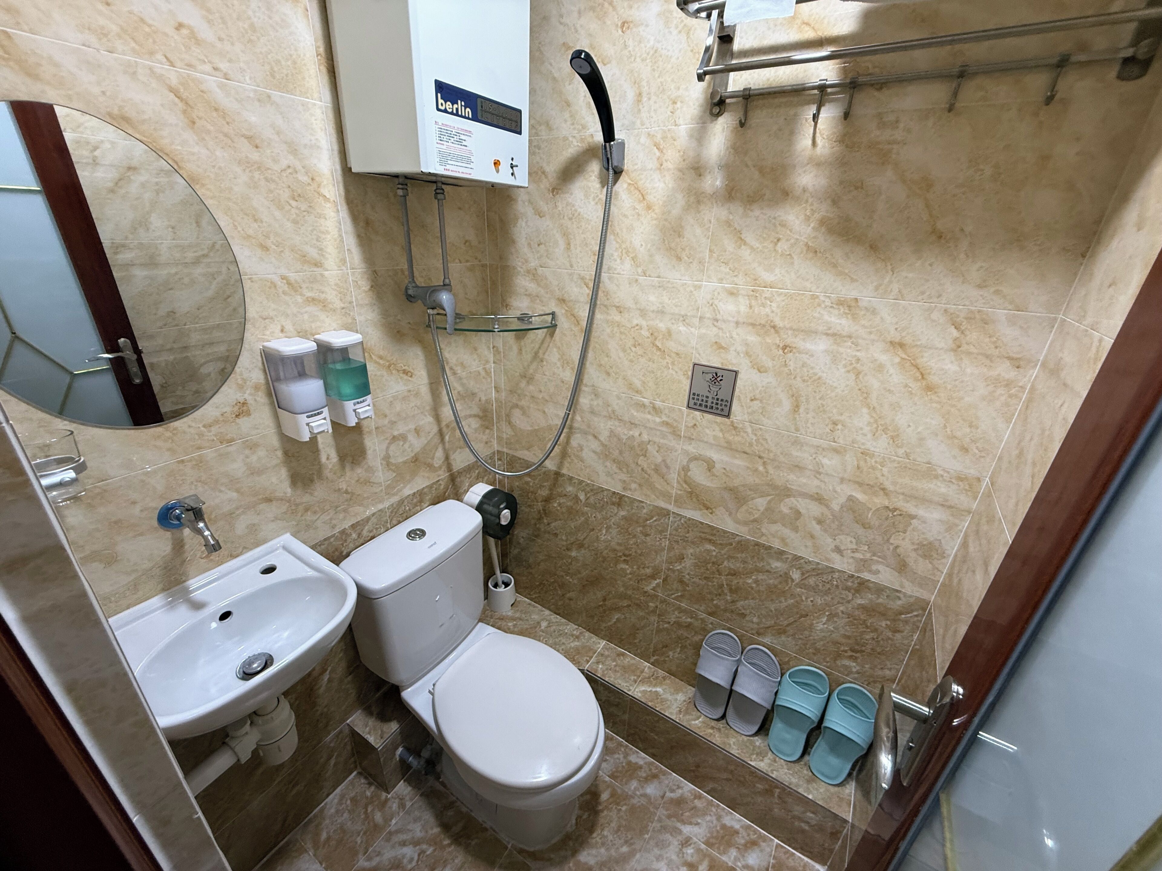 A bathroom with a toilet, sink, mirror, shower, and a towel rack.