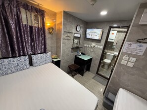 A hotel room with a bed, a bedside table, a TV, a bathroom with a toilet, and a shower. - Modern (Kowloon)