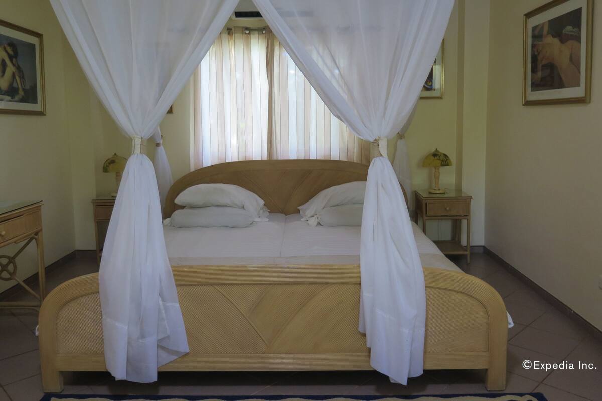 A bed with a wooden headboard, white bedding, and a canopy. There are two bedside tables with lamps.