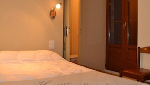 Een slaapkamer met een bed, een houten garderobe en een wandlamp.