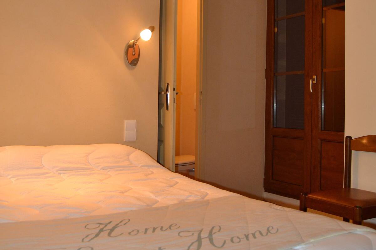 Un dormitorio con una cama, un armario de madera y una lámpara de pared.