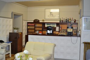 A hotel reception area with a counter displaying various amenities, a clock, and a framed picture on the wall. - Hôtel du Lion Vert (Luxeuil-les-Bains)